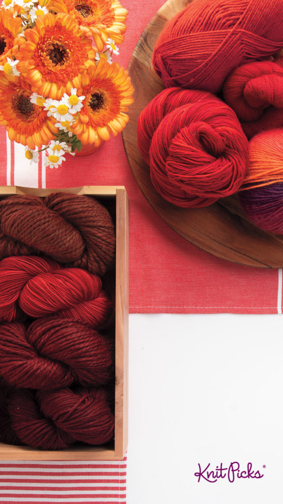 An image with an image of a pile of red yarn, a box of red yarn, and some yellow flowers