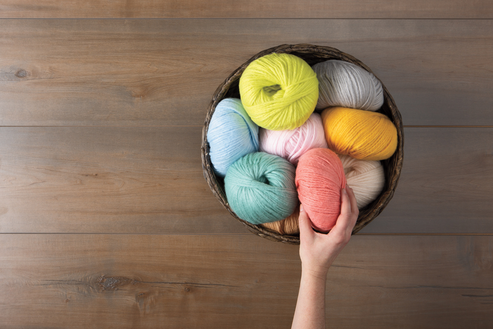 a bowl on a wood table filled with balls of Knit Picks Snuggle Puff Yarn.