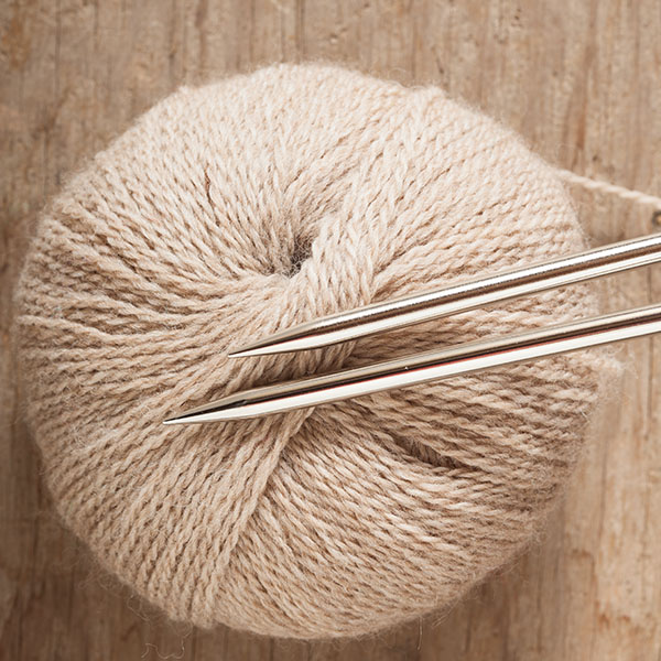 Sharp metal needles on top of a ball of yarn