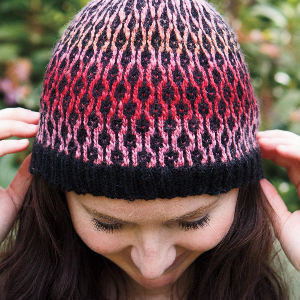 closeup of Links Hat - fingering weight version - a view from above the hat of a black & pink-toned stitch pattern that looks like black boxes linked together.