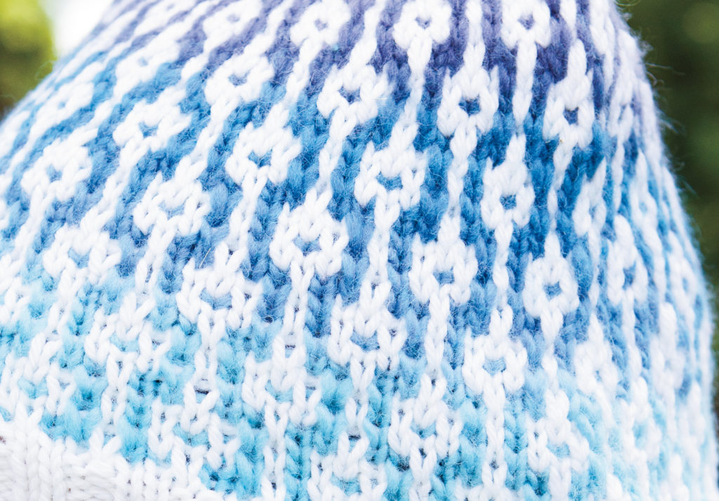 closeup of Links Hat - worsted weight version. Image description: a close-up view a mosaic knitting hat made of gradient blue and white stitches.