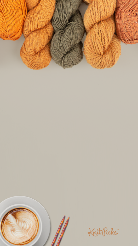 A taupe background with various orange yarns sticking out at the top of the frame. In the bottom left, a cup of coffee and some knitting needles.
